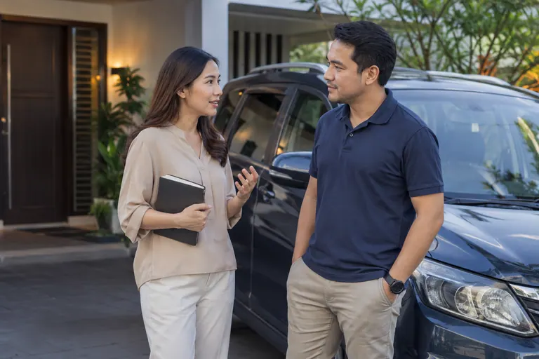 Dua orang berbincang di sebelah kenderaan diparkir di rumah