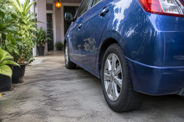 Roda belakang dan sisi hatchback biru yang diparkir di rumah